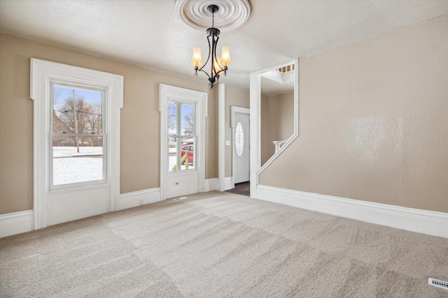 interior space featuring carpet, a textured ceiling, and an inviting chandelier