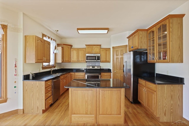 kitchen with sink, a kitchen island, stainless steel appliances, and light hardwood / wood-style floors