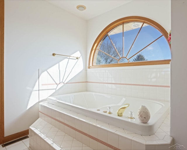 bathroom with tiled bath and tile patterned floors