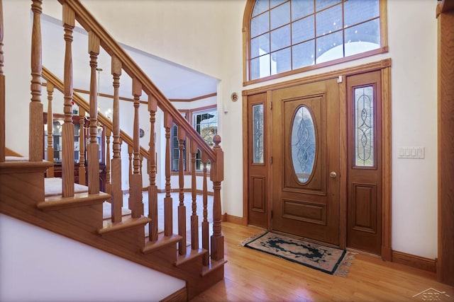 foyer entrance with a towering ceiling and light wood-type flooring