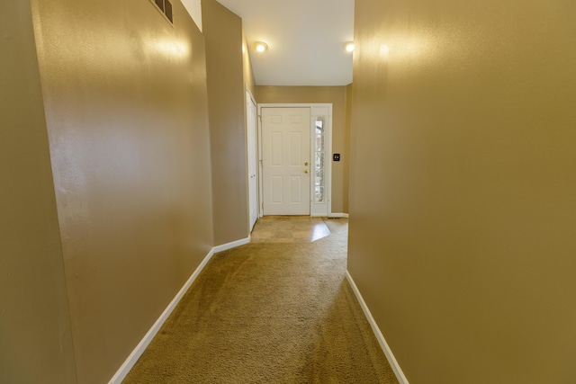 hallway featuring visible vents, baseboards, and carpet