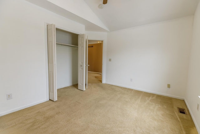 unfurnished bedroom featuring visible vents, baseboards, a closet, carpet, and lofted ceiling