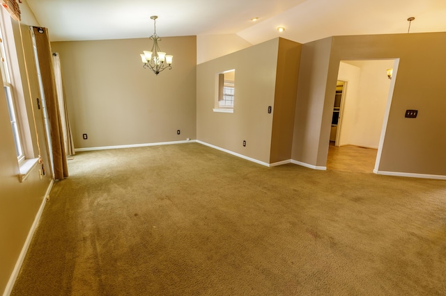 empty room featuring baseboards, carpet floors, a chandelier, and vaulted ceiling