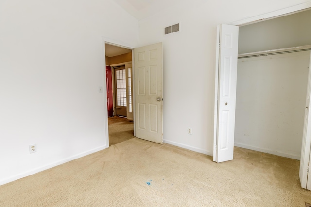 unfurnished bedroom featuring visible vents, a closet, carpet, baseboards, and vaulted ceiling