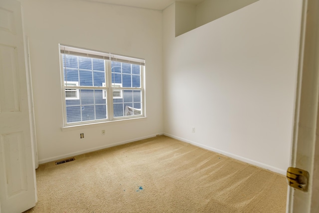 empty room featuring visible vents, baseboards, and light colored carpet