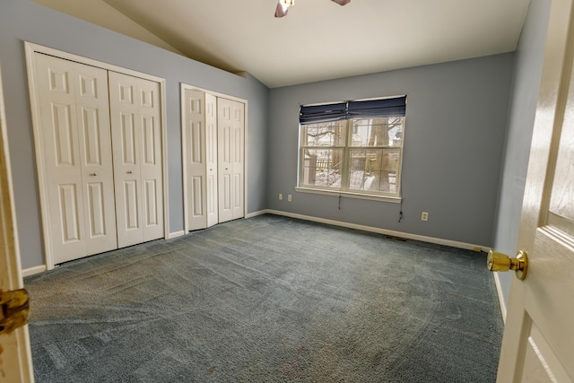 unfurnished bedroom with vaulted ceiling, carpet flooring, baseboards, and two closets