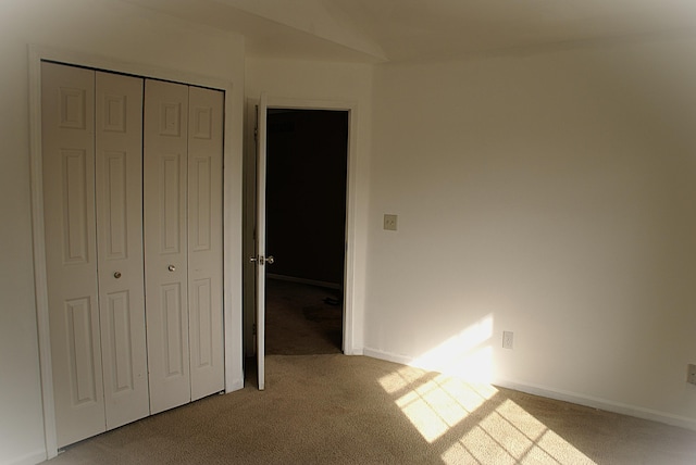 unfurnished bedroom with carpet flooring, baseboards, and a closet