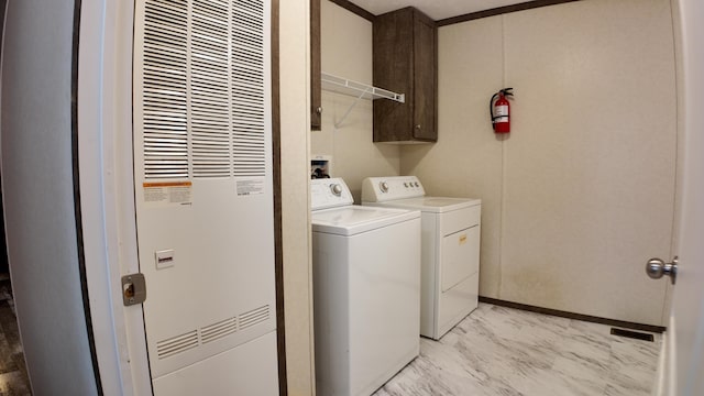 laundry area featuring washing machine and dryer, cabinets, and ornamental molding