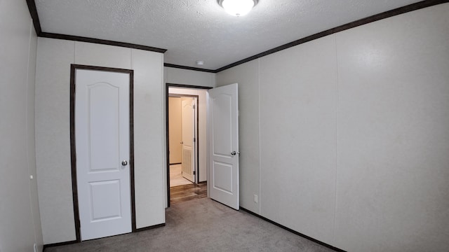 unfurnished bedroom featuring light carpet, a textured ceiling, and crown molding