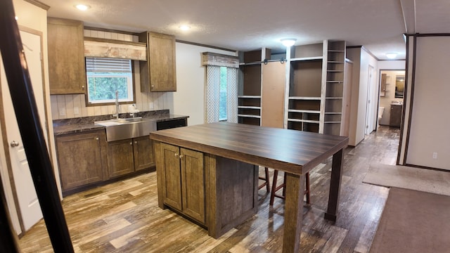 kitchen with sink, tasteful backsplash, hardwood / wood-style floors, a textured ceiling, and ornamental molding