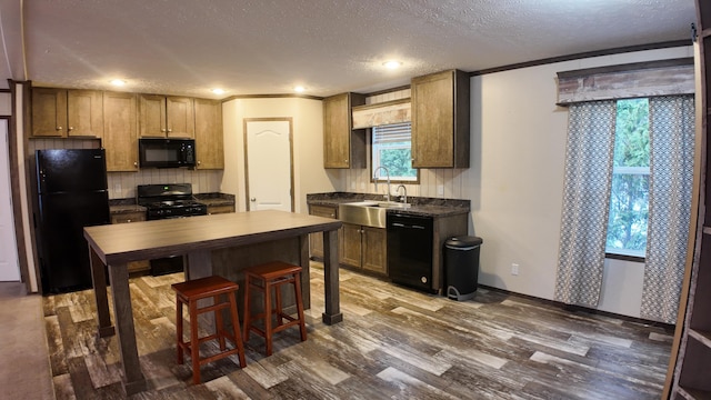 kitchen featuring dark wood-type flooring, black appliances, crown molding, sink, and a textured ceiling