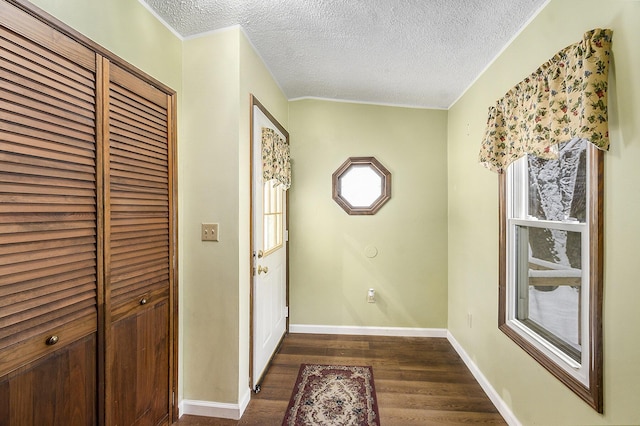 doorway to outside featuring a textured ceiling, crown molding, and dark wood-type flooring