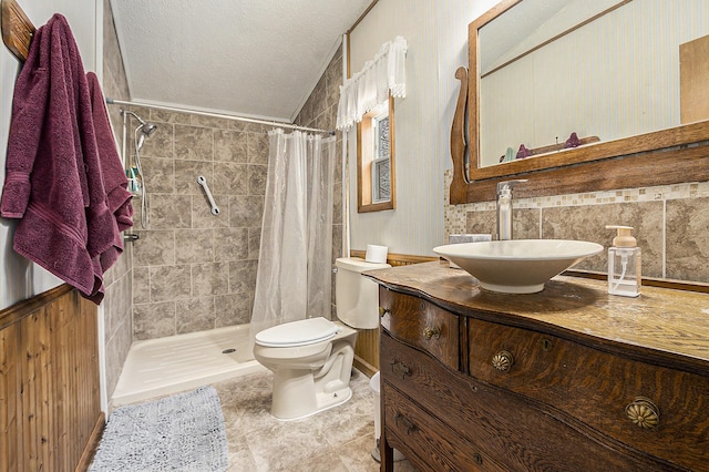 bathroom featuring tile patterned floors, a textured ceiling, vanity, tile walls, and toilet