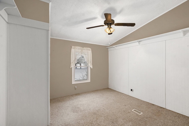 carpeted spare room featuring ornamental molding, a textured ceiling, ceiling fan, and lofted ceiling