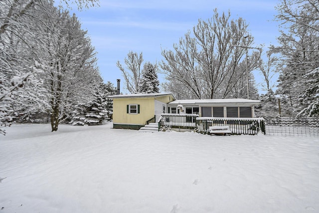 snow covered back of property featuring a wooden deck