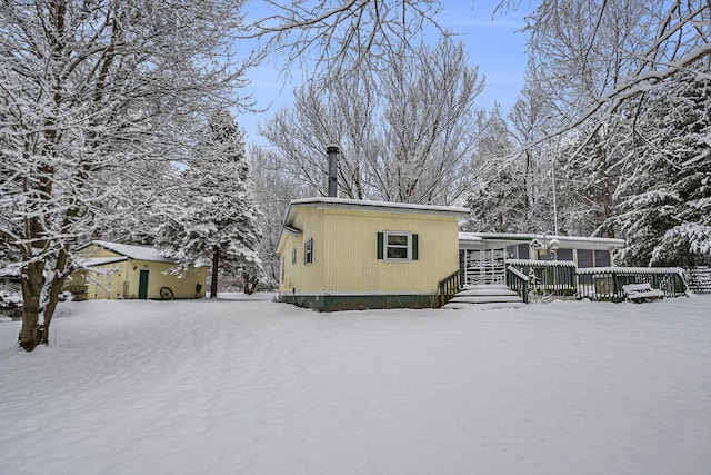 snow covered back of property with a wooden deck