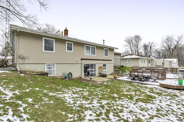 snow covered rear of property featuring a lawn