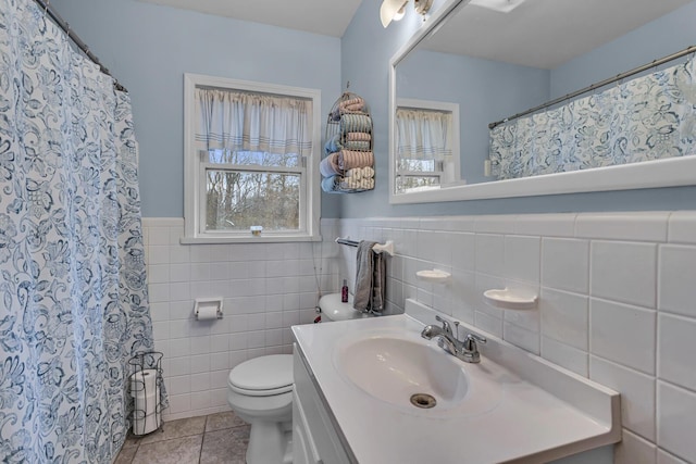 bathroom featuring tile patterned flooring, vanity, toilet, and tile walls