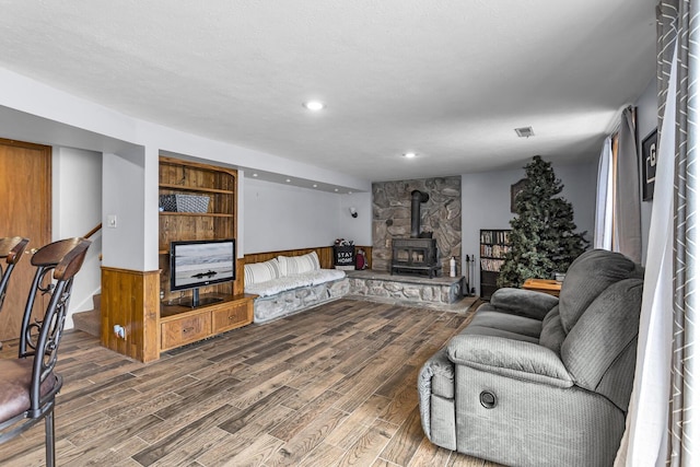 living room featuring hardwood / wood-style floors, a textured ceiling, and a wood stove