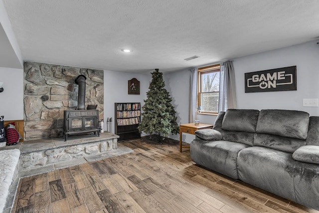 living room with a wood stove, hardwood / wood-style floors, and a textured ceiling