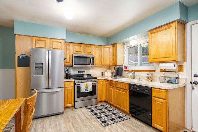 kitchen with sink, stainless steel appliances, and light hardwood / wood-style flooring