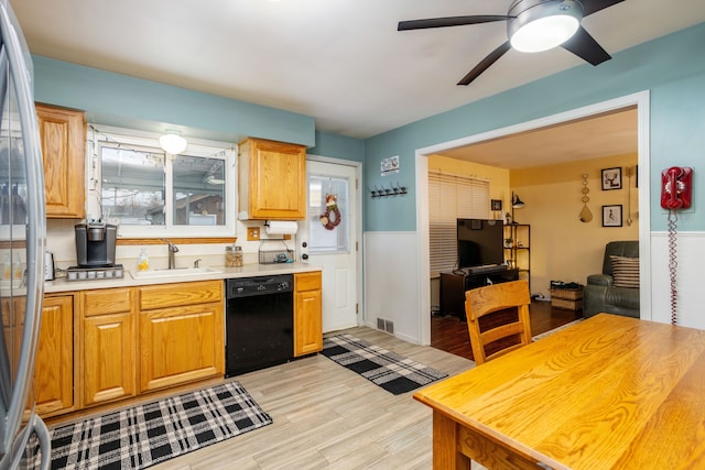 kitchen with sink, ceiling fan, light wood-type flooring, black dishwasher, and stainless steel refrigerator