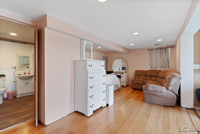 sitting room with a textured ceiling, light wood-type flooring, and sink