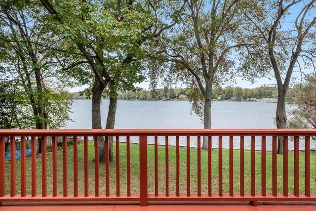 wooden terrace with a water view and a lawn