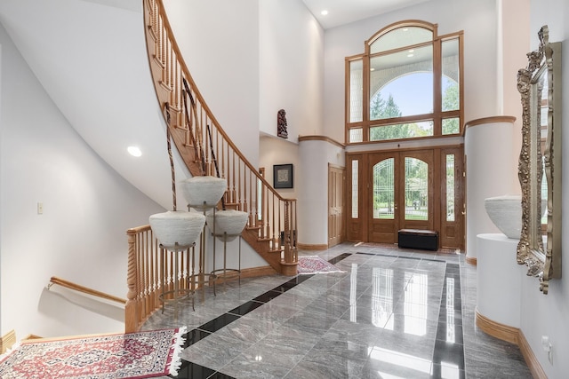 entrance foyer with french doors, a towering ceiling, and plenty of natural light
