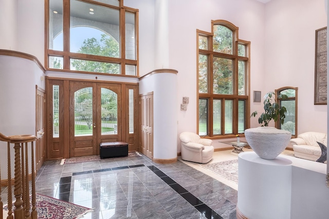 foyer entrance with french doors, a towering ceiling, and a healthy amount of sunlight