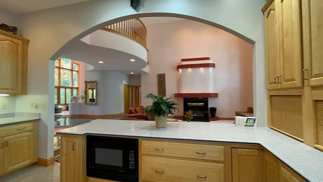 kitchen with kitchen peninsula, black microwave, and light brown cabinetry