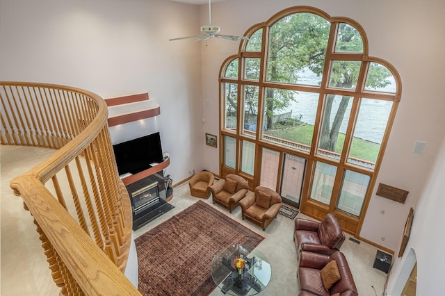 carpeted living room with ceiling fan and a high ceiling