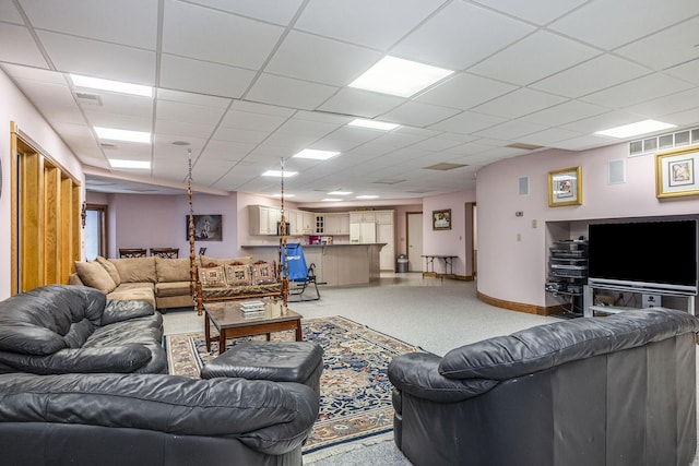 carpeted living room with a paneled ceiling