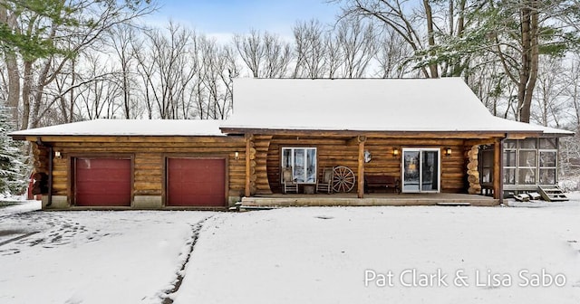 log-style house featuring covered porch and a garage