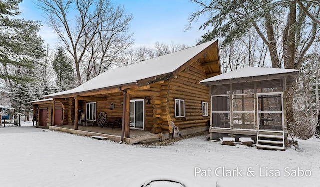 snow covered house featuring a sunroom