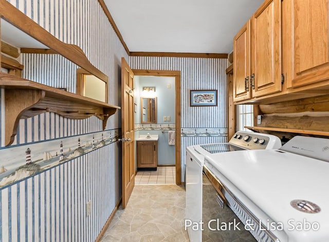 clothes washing area featuring cabinets, washing machine and dryer, ornamental molding, and sink