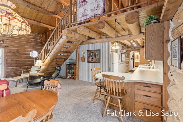 carpeted dining space featuring vaulted ceiling with beams, wooden ceiling, and sink