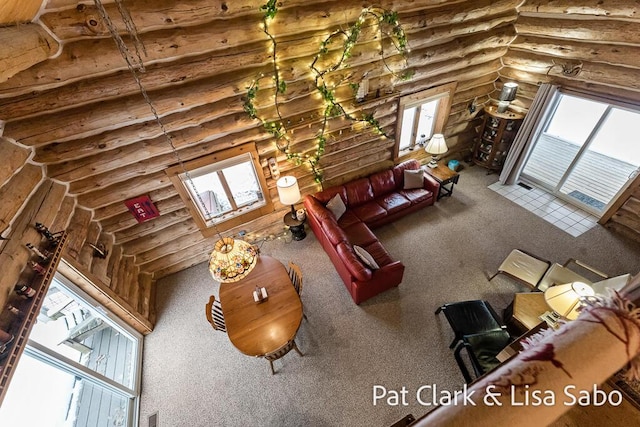 unfurnished living room with a healthy amount of sunlight, carpet floors, and log walls