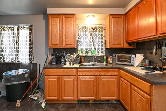 kitchen with dark tile patterned flooring, a healthy amount of sunlight, sink, and tasteful backsplash