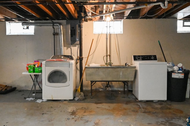 basement with electric panel, washer and clothes dryer, and sink