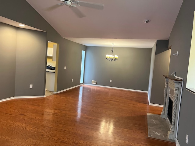 unfurnished living room with hardwood / wood-style floors, ceiling fan with notable chandelier, and lofted ceiling