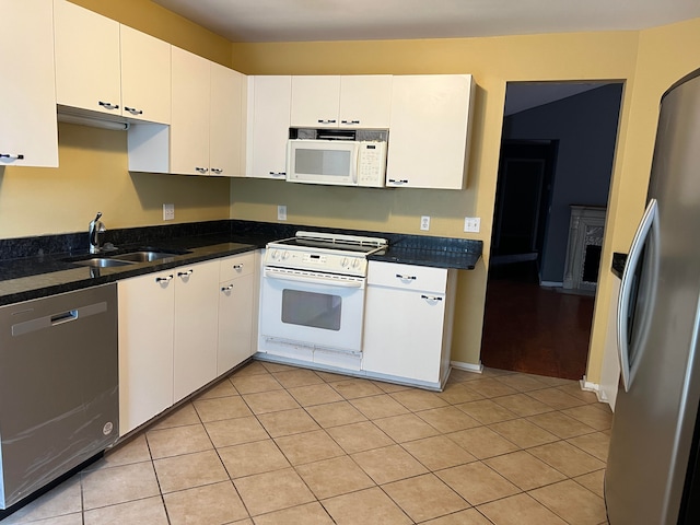 kitchen with sink, white cabinetry, stainless steel appliances, and dark stone counters