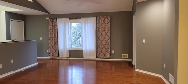 empty room featuring hardwood / wood-style floors and vaulted ceiling