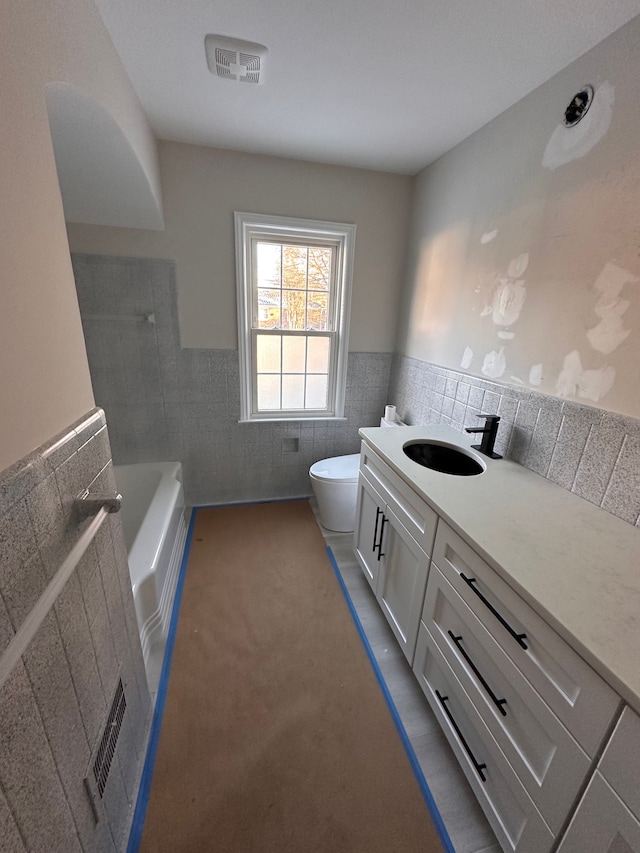 bathroom featuring vanity, a bathtub, toilet, and tile walls