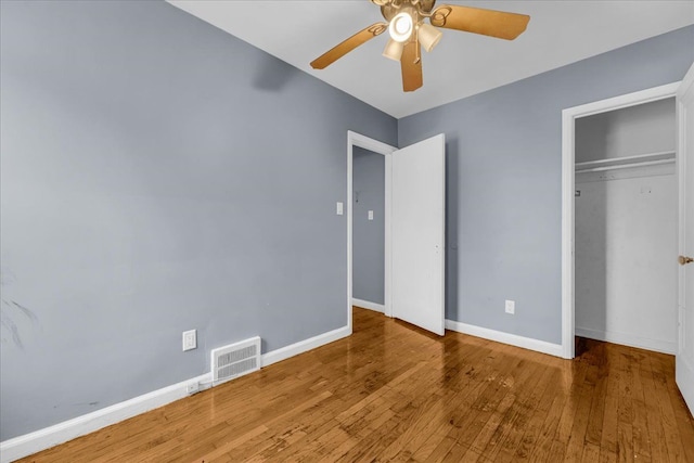 unfurnished bedroom featuring hardwood / wood-style flooring, ceiling fan, and a closet