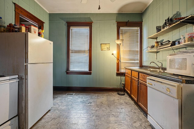 kitchen with white appliances, crown molding, sink, wooden walls, and ceiling fan