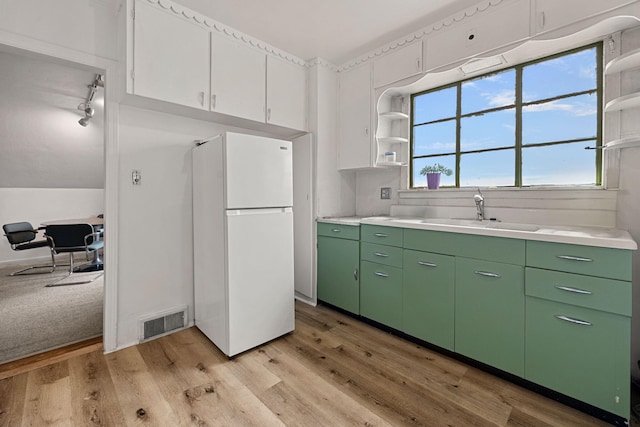 kitchen featuring light wood-type flooring, white fridge, white cabinetry, and sink