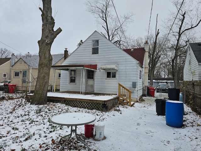 snow covered back of property featuring a deck