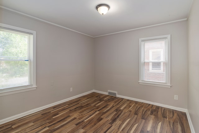 empty room with crown molding, a wealth of natural light, and dark wood-type flooring