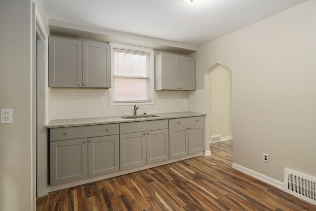 kitchen featuring backsplash, dark hardwood / wood-style floors, gray cabinetry, and sink